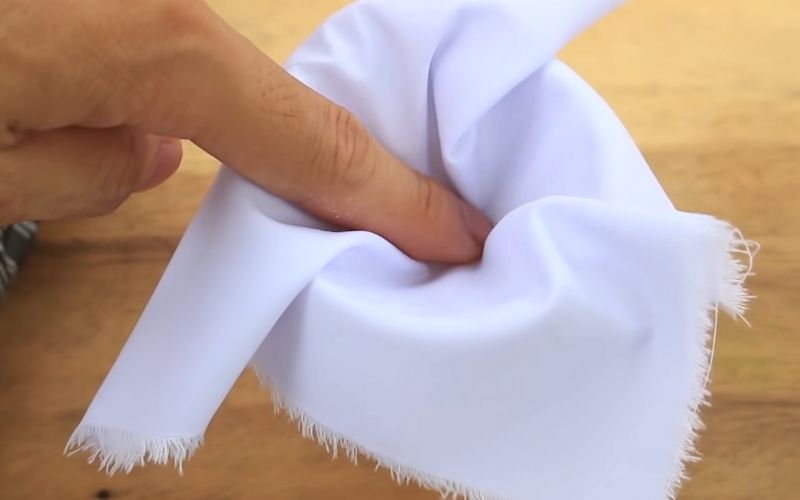 Đặt miếng vải lên miệng cốc rồi dùng tay ấn miếng vải cho đến khi hơi lõm xuống